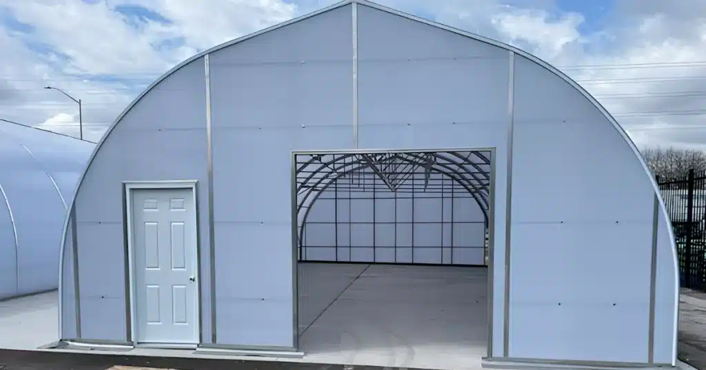 Front gable end of Ovaltech III commercial greenhouse in ontario showing open 96x98-inch double sliding door and 34x80-inch steel entry door, Canadian Tire Barrhaven Ontario
